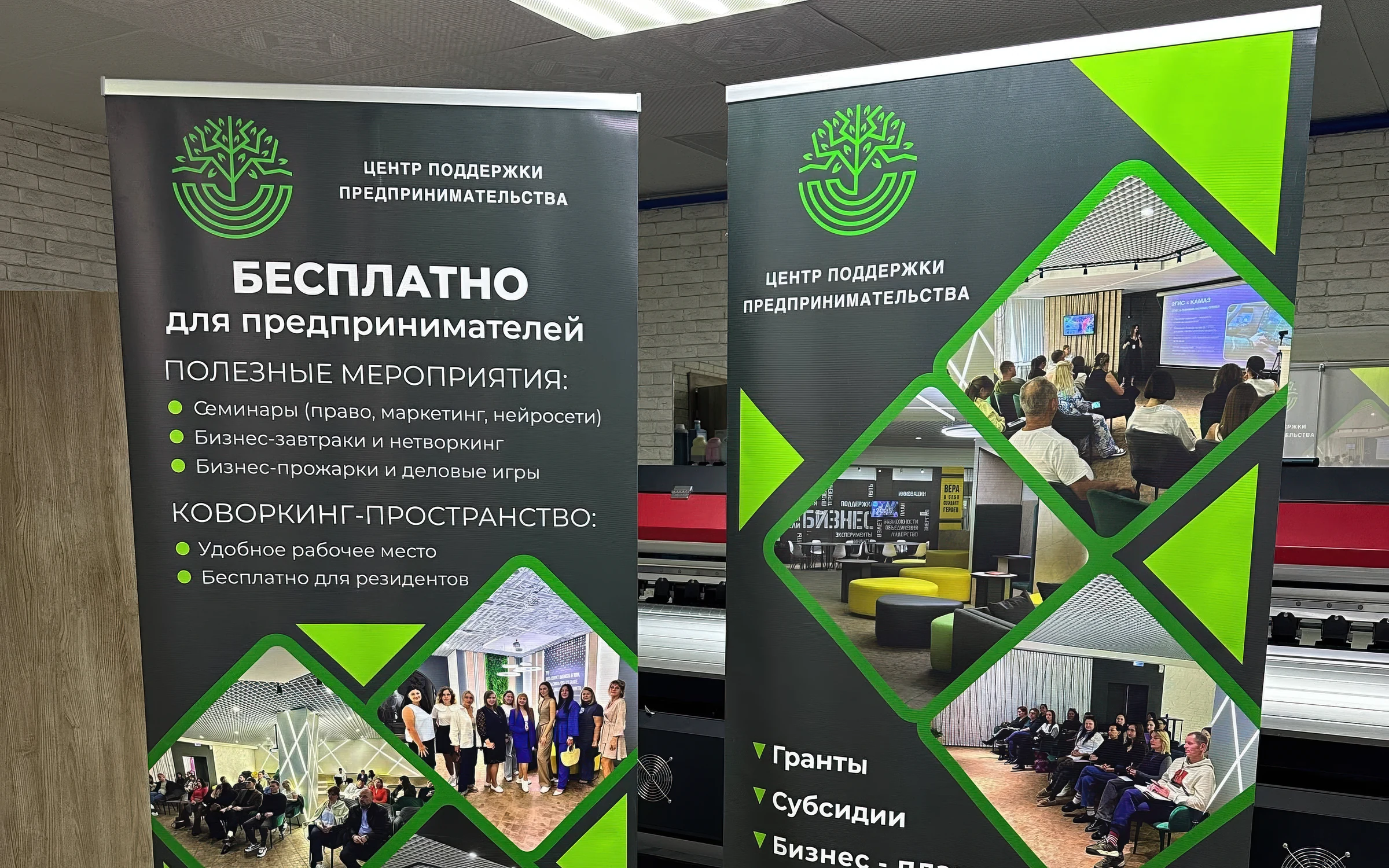 Два напечатанных роллапа для центра поддержки предпринимательства на фоне широкоформатного принтера